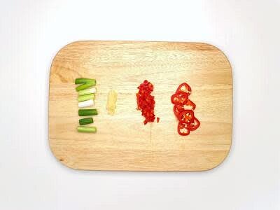 Meanwhile, boil a kettle Trim, then chop the spring onion[s] into large pieces Peel and finely chop (or grate) the garlic Cut half the red chilli[es] in half lengthways, deseed (scrape the seeds out with a teaspoon) and chop finely Slice the remaining red chilli finely