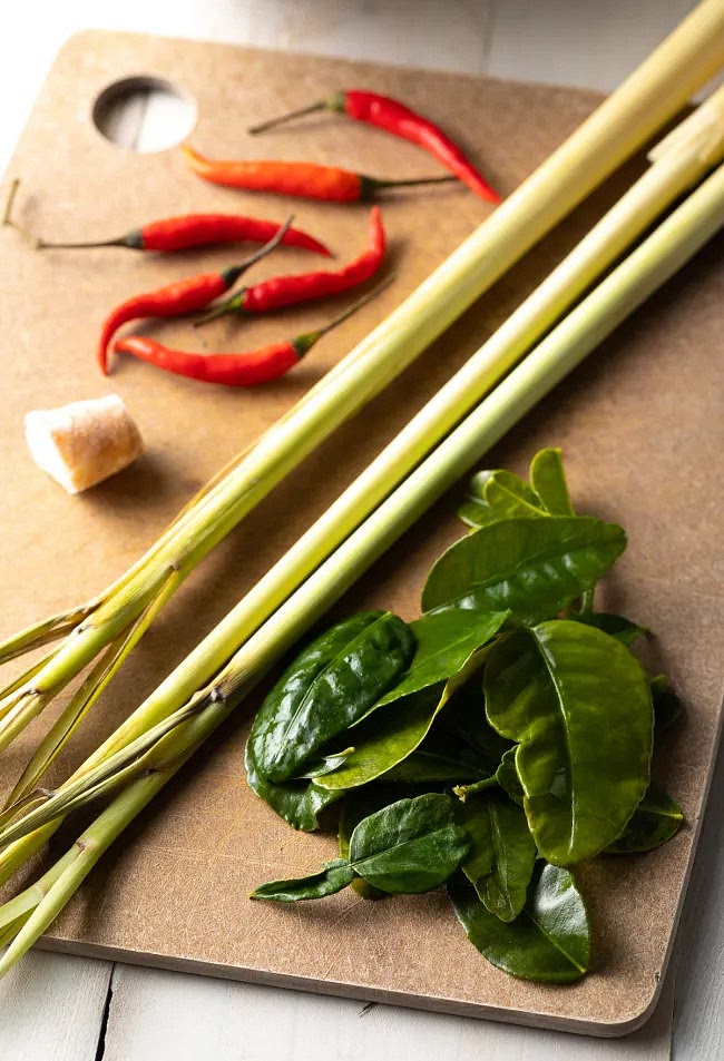 Using a meat mallet or the side of a knife, smash the lemongrass, kaffir lime leaves, onion, chilies, and galangal. Place them in a medium soup pot. Pour the water into the pot then bring to a boil. Reduce the heat and simmer for 5-10 minutes, until the broth smells bright and fragrant.