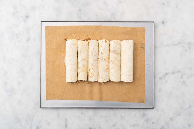 On a clean surface, arrange tortillas. Using a slotted spoon, divide meat mixture down the middle of each tortilla. Sprinkle cheese over top. Roll tortillas tightly over filling, then arrange tacquitos on a parchment-lined baking sheet, seam side down. Brush tops with 1 Tbsp oil. Bake in the middle of the oven until golden-brown (6-8 min).