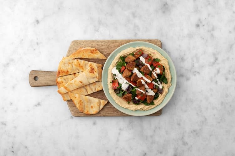 Cut flatbreads into wedges. Divide hummus between plates, then spread into an even layer. Top with roasted veggies, then crispy falafel. Drizzle over garlic-Parmesan dressing.
