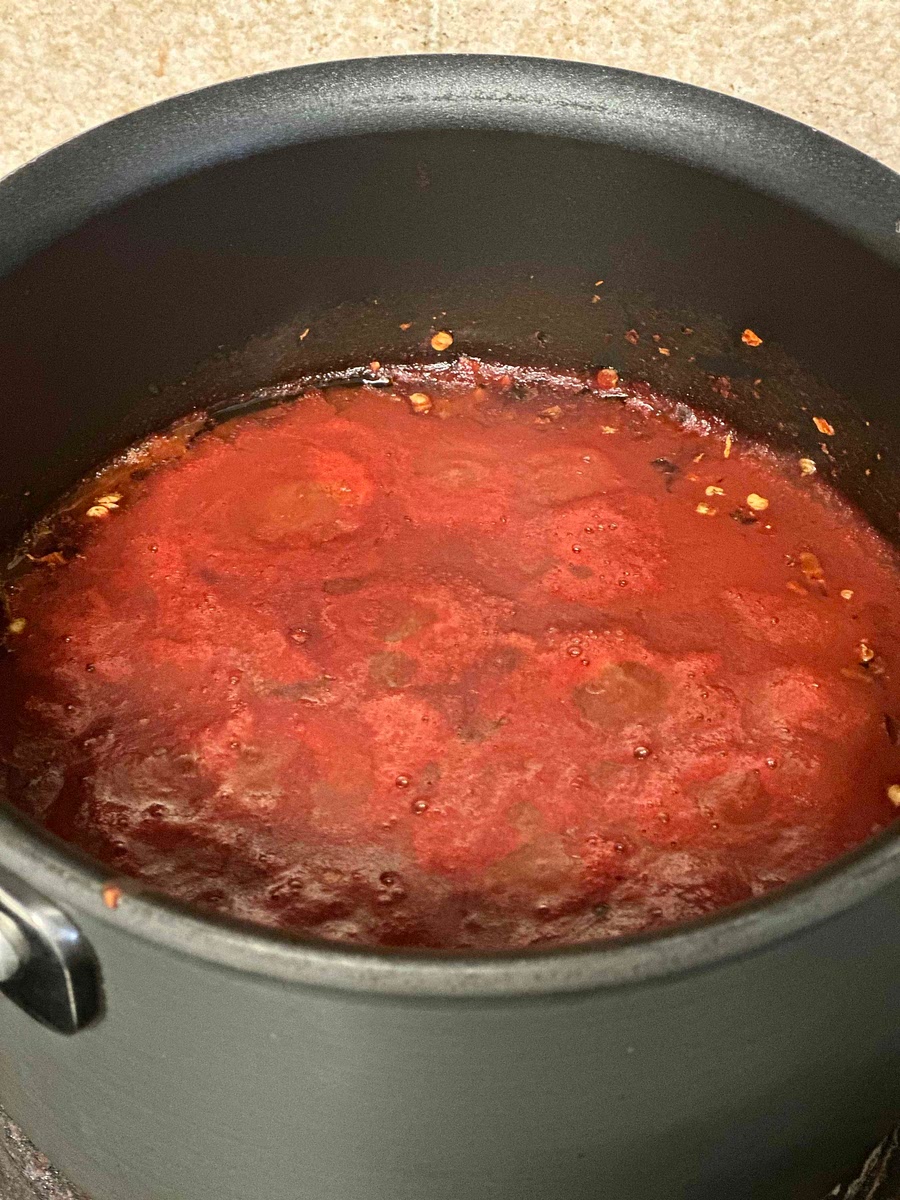 In a saucepan, cook the tomato sauce and the red pepper flakes over low heat on the back burner of the stove.