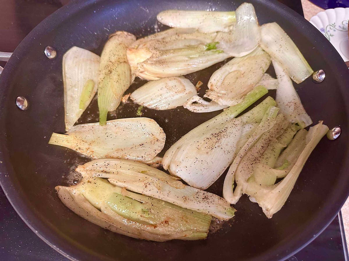 Cut the base off of the fennel bulbs, and cut a cone shape into the base to remove the core. You can see the core because it is whiter than the surrounding green. This is optional, but helps the fennel cook faster. Slice the fennel vertically (upright) into 1/4 inch thick slices.