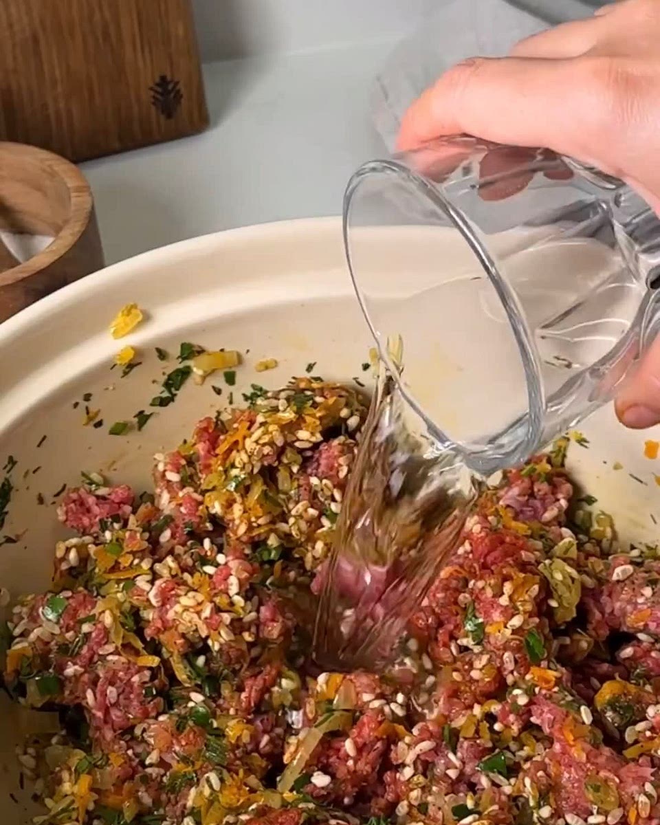 Добавляем к фаршу зажарку из моркови и лука, рис, специи, соль, зелень, 1/2 стакана воды и перемешиваем