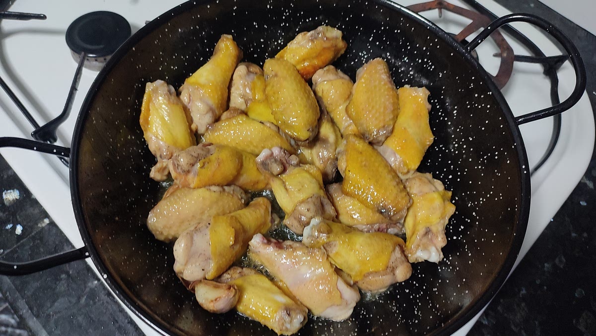 En una olla o perol amplio, hacemos el fondo con abundante aceite y una vez caliente freimos las alitas salpimentadas con los dientes de ajos enteros.