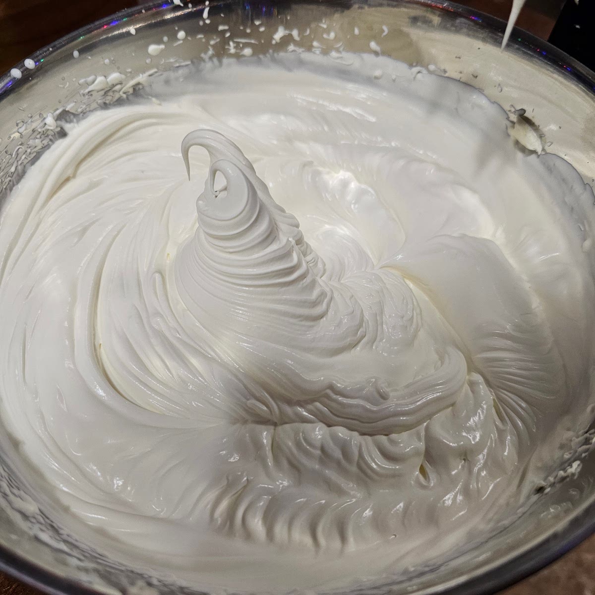 Add your heavy cream to the mascarpone. You're going to whip this to very stiff peaks. It should stand on its own. This will take a long time if you're making many servings. See the picture and how it stands up on its own.