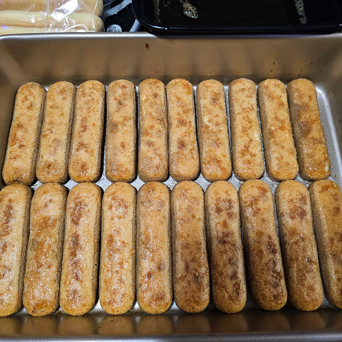 Get your container for the Tiramisu, it would be easiest of you had a spring form pan of some sort, though I typically use a baking pan. Dip the lady finger in for 2 or so seconds, rotate it to the other side, for 2 or so seconds, then rotate again and pull it out. You won't be able to leave them in for too long without them falling apart in your hands. You just want to make sure it soaks enough coffee mix to not be crunchy. You'll want to have the bottom layer of lady fingers to be very tight together. This makes it easier to scoop out of the pan. See the picture.