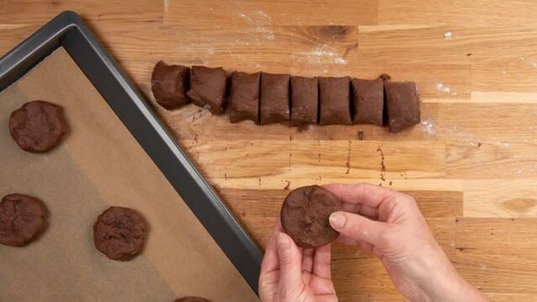 Anschließend formst du die Stücke mit den Händen zu flachen Talern mit etwa 5 cm Durchmesser. Lege sie dann auch schon auf das vorbereitete Backblech. Lass dabei immer 5 cm Abstand, so laufen die Cookies beim Backen nicht zusammen.