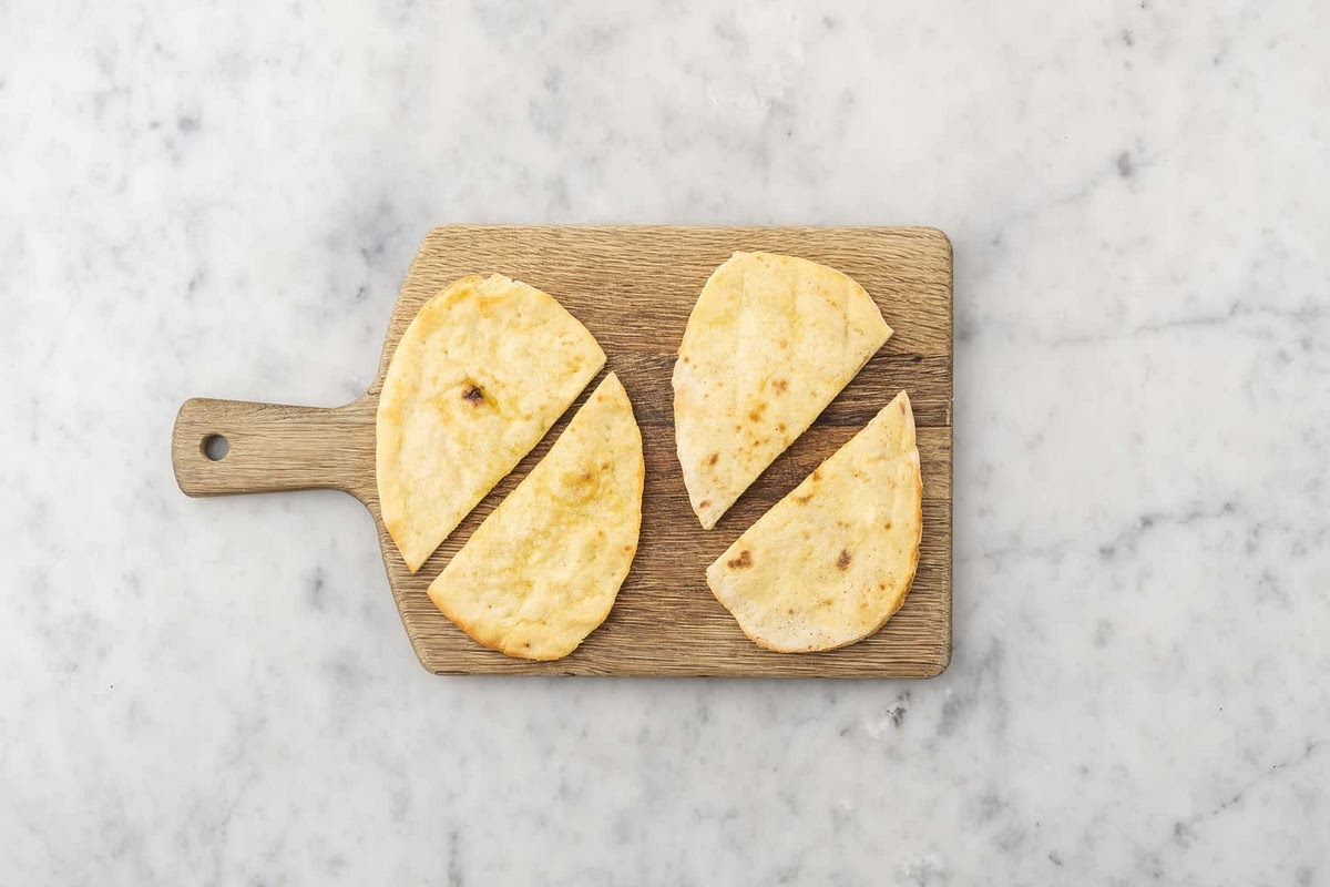 a) Cut the naans in half widthways, then put in your toaster until golden. If you're using the oven, put the naans onto a baking tray. Sprinkle with a little water and pop them into the oven to warm through, 2-3 mins.
b) Add the rocket to the tomato bowl. Toss to coat.