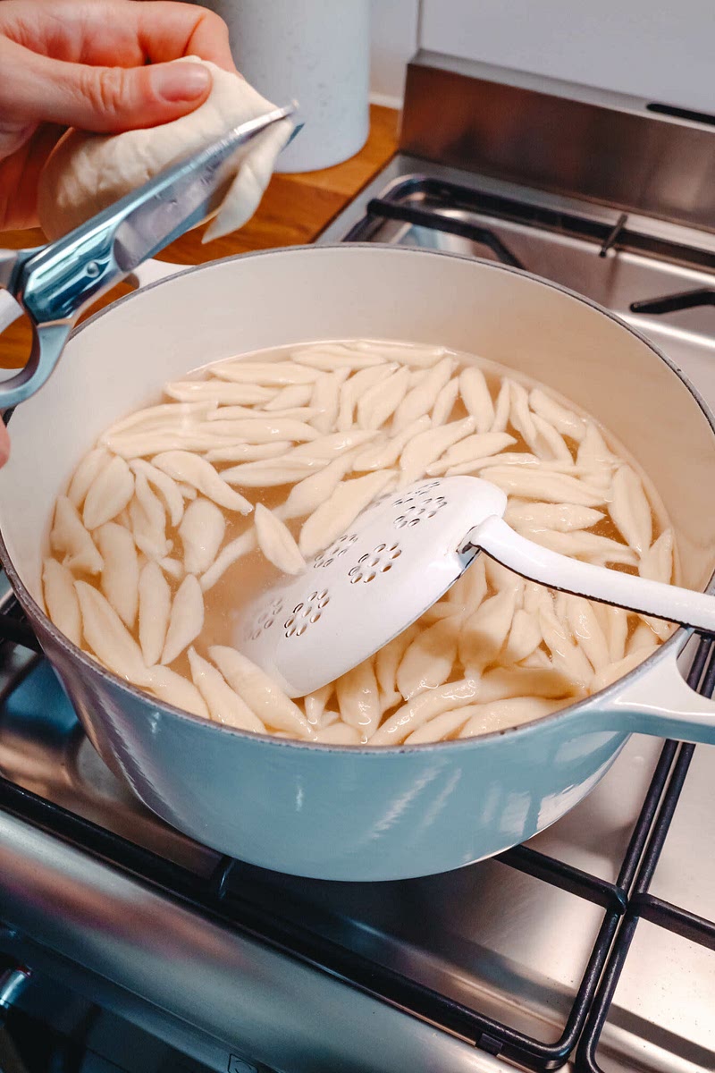 Etwa 1 l Wasser zum Kochen bringen. Teig aus dem Kühlschrank nehmen und erneut kurz durchkneten. Mit einer leicht eingeölten Schere etwa 3 cm lange, nicht zu dicke Nudeln direkt ins köchelnde Wasser schneiden (siehe Tipp). 6–8 Minuten nicht zu stark kochen lassen, dabei gelegentlich umrühren.