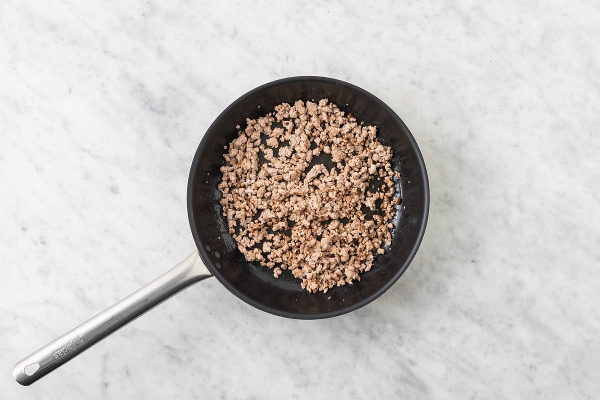 Once hot, fry the pork mince, 5-6 mins. Break up the mince as it cooks. IMPORTANT: Wash hands and utensils after handling raw meat. Cook so there's no pink in the middle.
Meanwhile, grate the cheese.
In a bowl, mix together the burger sauce and coleslaw mix. Season with salt and pepper.