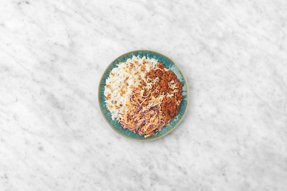 Share your rice between bowls.
Top with the spiced pork mince and coleslaw.
Sprinkle the cheese and crispy onions all over.