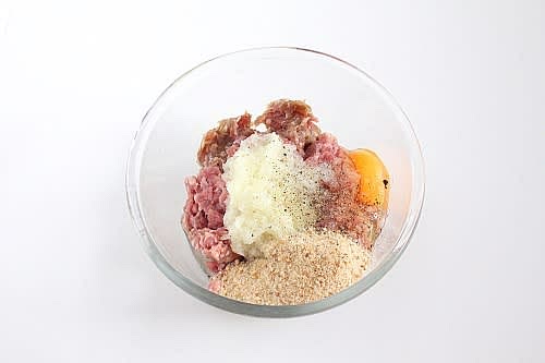 В миску к фаршу вбить куриное яйцо, добавить пару столовых ложек панировачных сухарей, соль, перец и содержимое блендера вместе со всей жидкостью.