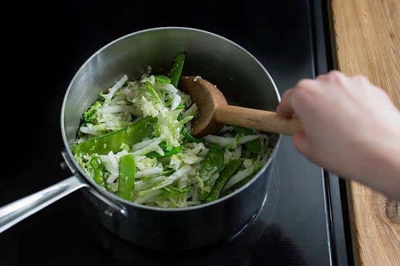 Sauté the vegetables
Thinly slice the scallions crosswise. In the reserved pot, heat a drizzle of oil on medium-high. Add the remaining garlic and ½ the scallions. Sauté, 30 sec. to 1 min., until softened and fragrant. Add the string peas, cabbage and S&P. Sauté, 1 to 2 min., until crisp-tender.