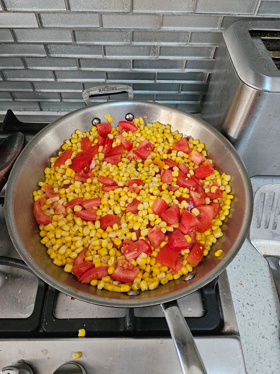 While rice cooks, cut tomato into bite sized chunks. Drain corn. Fry tomato and corn in olive oil for 5 or so min.