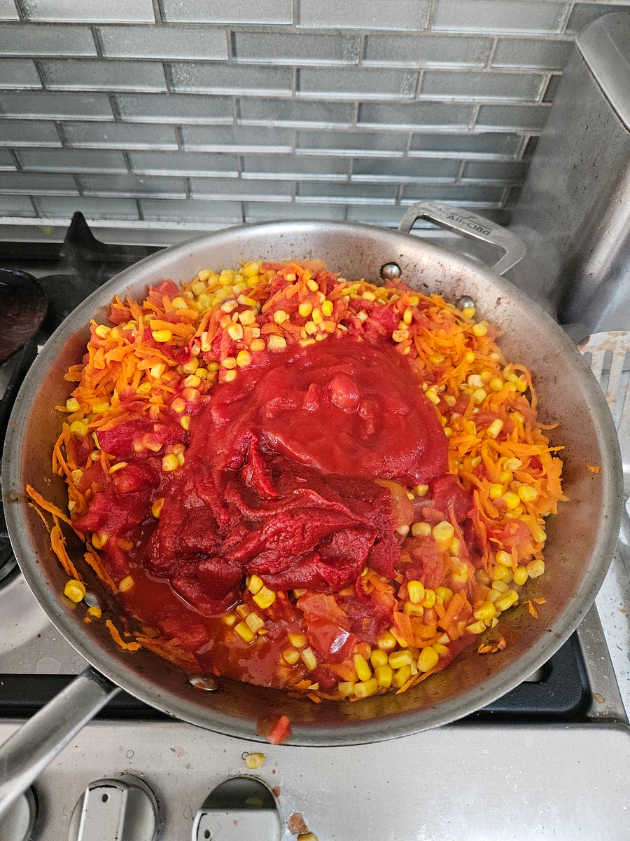 While tomato/corn cooks, peel then grate carrot, then add stock and carrot to the tomato and corn mixture and fry for a couple more min. Add the tins of tomatoes and the tomato paste and reduce.