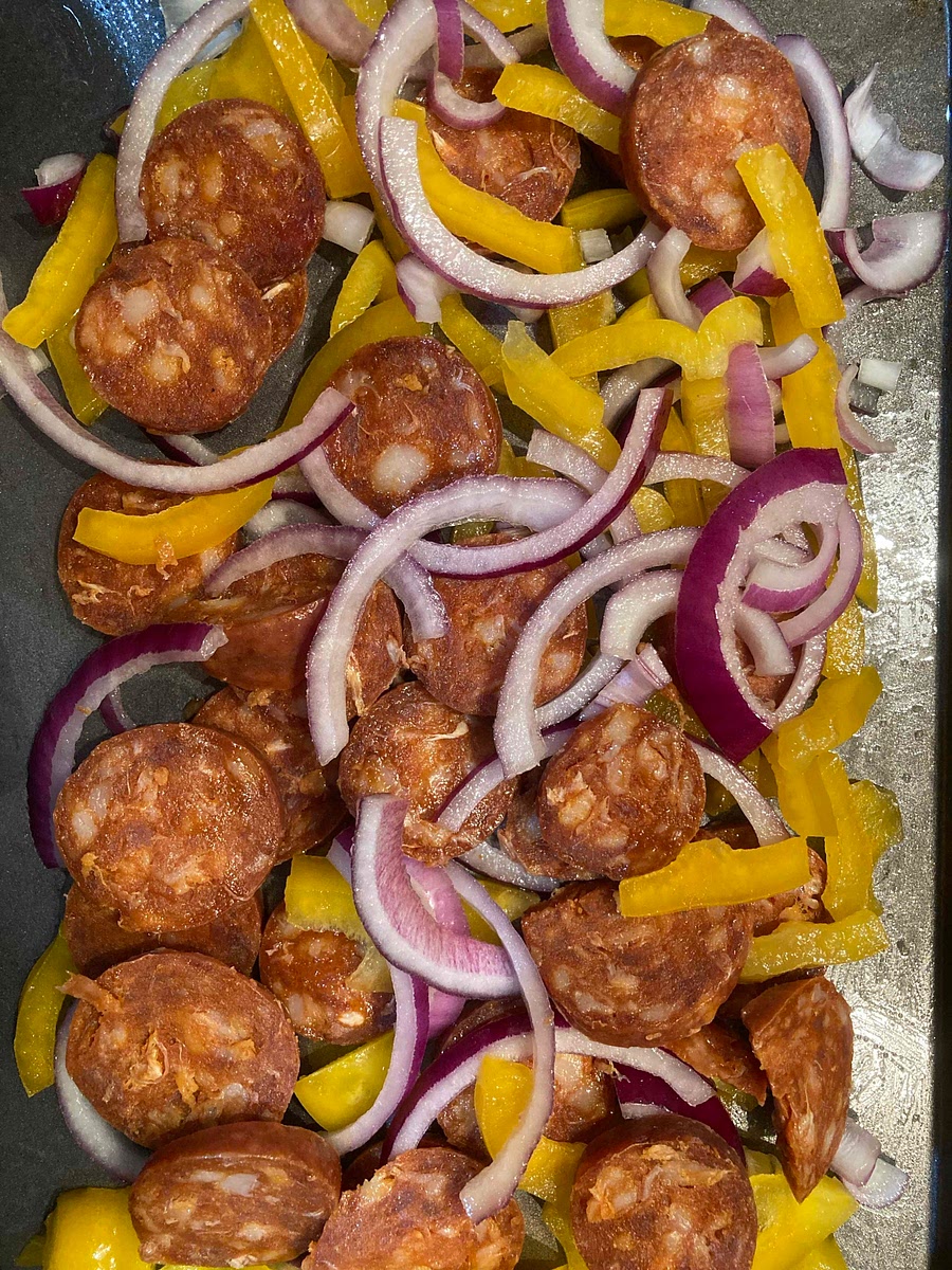 Put the onion and yellow pepper on a large baking tray and drizzle over the oil. Add the chorizo to the tray and bake for 15 mins.