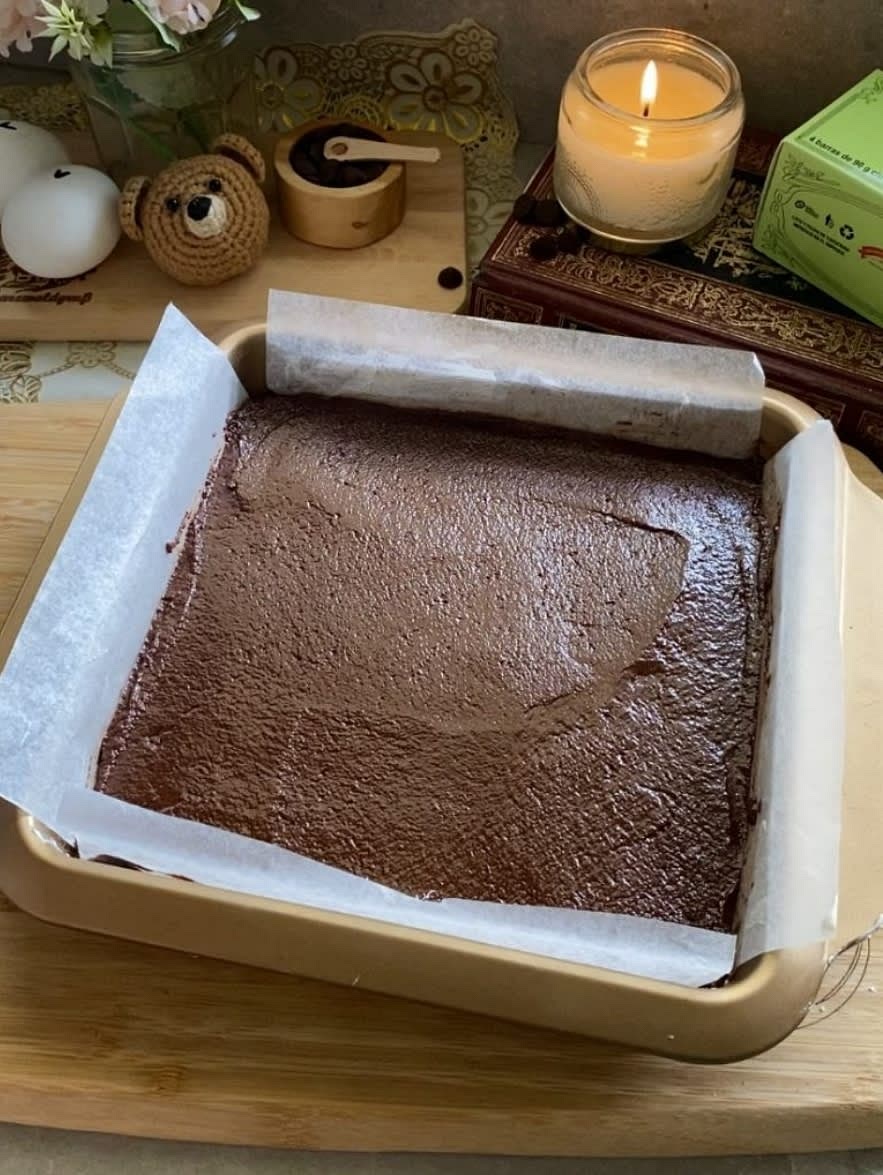 Apartar dos cucharadas de masa de brownie para la decoracion. En un molde cuadrado cin papel encerado, verter el resto de la masa de brownie y emparejar