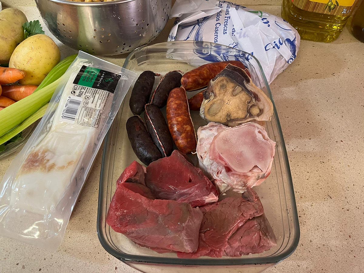 Echamos los huesos, la carne, el pollo, el tocino, todos los puerros menos un cacho para echarlo más tarde y que quede de compango, los ajos, el laurel y los garbanzos. Podemos guardar un puerro para echarle luego si nos gusta como compango.