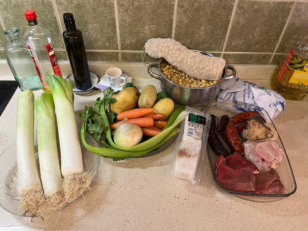 Pelamos todas las verduras y limpiamos la carne. Escurrimos y lavamos los garbanzos y los metemos en una malla si tenemos.