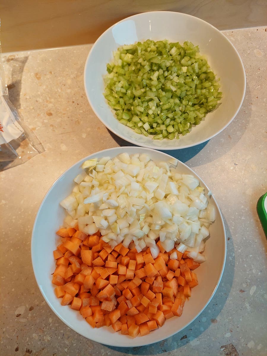 Prepare by finely dicing the carrots and celery. Dice the onion. Put the carrot and onion in the same bowl, then celery in another. Keep the cutting board out for the garlic later.