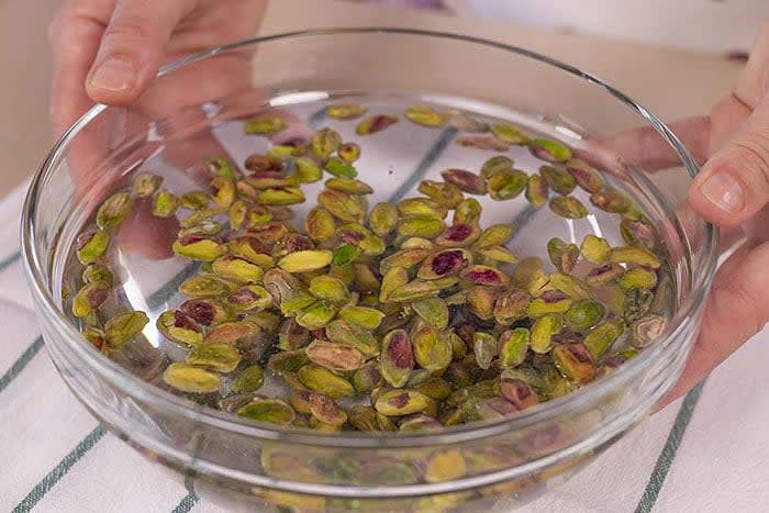 mettiamo i pistacchi a bagno in acqua fredda per almeno 12 ore. Questa operazione faciliterà la rimozione della pellicina esterna dei pistacchi mantenendo il colore verde inalterato.
