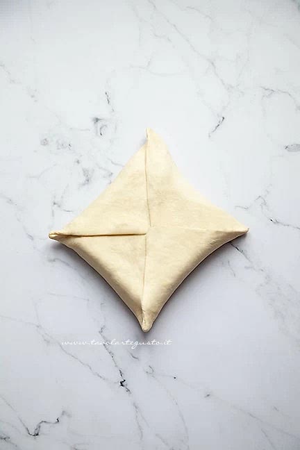 Poi sollevate i 4 lembi di impasto e senza sovrapporli troppo, ripiegateli sul burro formando un pacchetto: