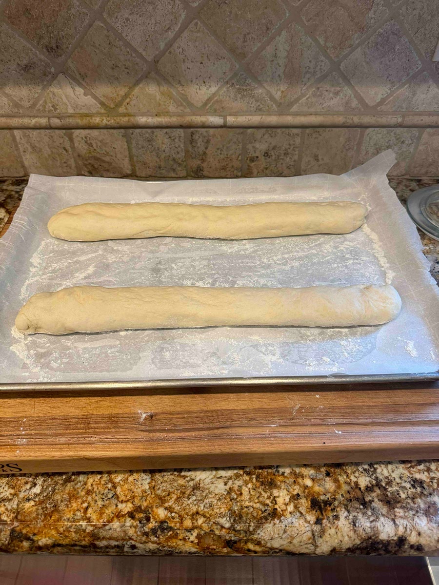 Place the rolled dough onto the sheet pan and begin to roll back and forth slightly stretching the dough until it is just slightly shorter than the length of the pan. Rolling back and forth will help seal the dough. When stretching the dough make sure the dough is roughly the same circumference throughout the entire loaf.