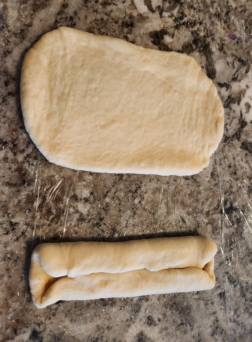 Shape each piece into a ball and then use the roller again to make each piece into a rectangle. Shape into a 5-6" hot dog bun with the edges folded under.
