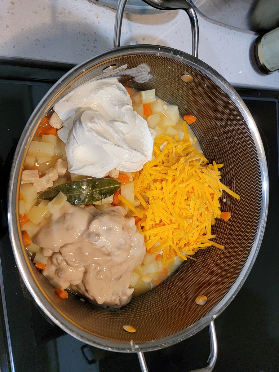 5. Stir in sour cream, Cheddar cheese and can of condensed Cream of Mushroom Soup. Once fully incorporated and the cheese is completely melted, remove from heat. Pour or spoon filling into greased casserole dish. Remove bay leaves.