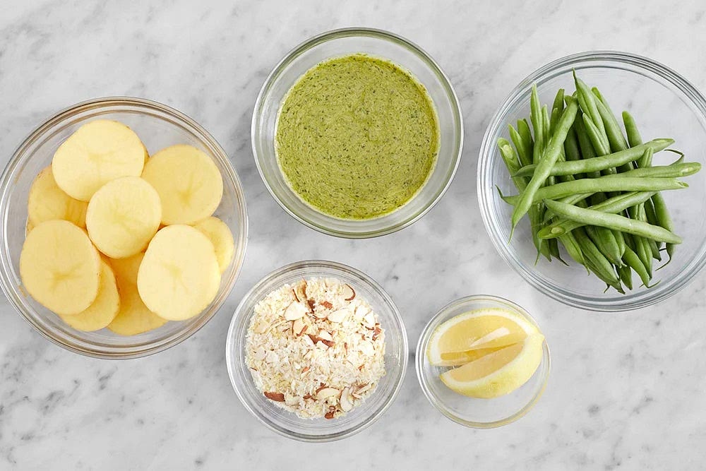 Preheat the oven to 450°F. Wash and dry the fresh produce. Cut the potatoes into 1/2-inch rounds. Cut off and discard any stem ends from the green beans. Using a zester or the small side of a box grater, finely grate the lemon to get 2 teaspoons of zest. Quarter and deseed the lemon. Roughly chop the almonds. In a bowl, combine the pesto, mayonnaise, and the juice of 2 lemon wedges. Season with salt and pepper. In a separate bowl, combine the breadcrumbs, lemon zest, and chopped almonds.