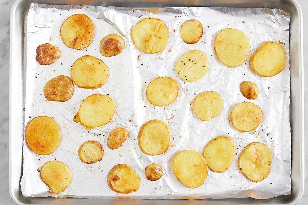 Line two sheet pans with foil. Transfer the potato rounds to one sheet pan. Drizzle with olive oil; season with salt and pepper. Toss to coat and arrange in an even layer. Roast 19 to 21 minutes, or until lightly browned and tender when pierced with a fork. Remove from the oven.