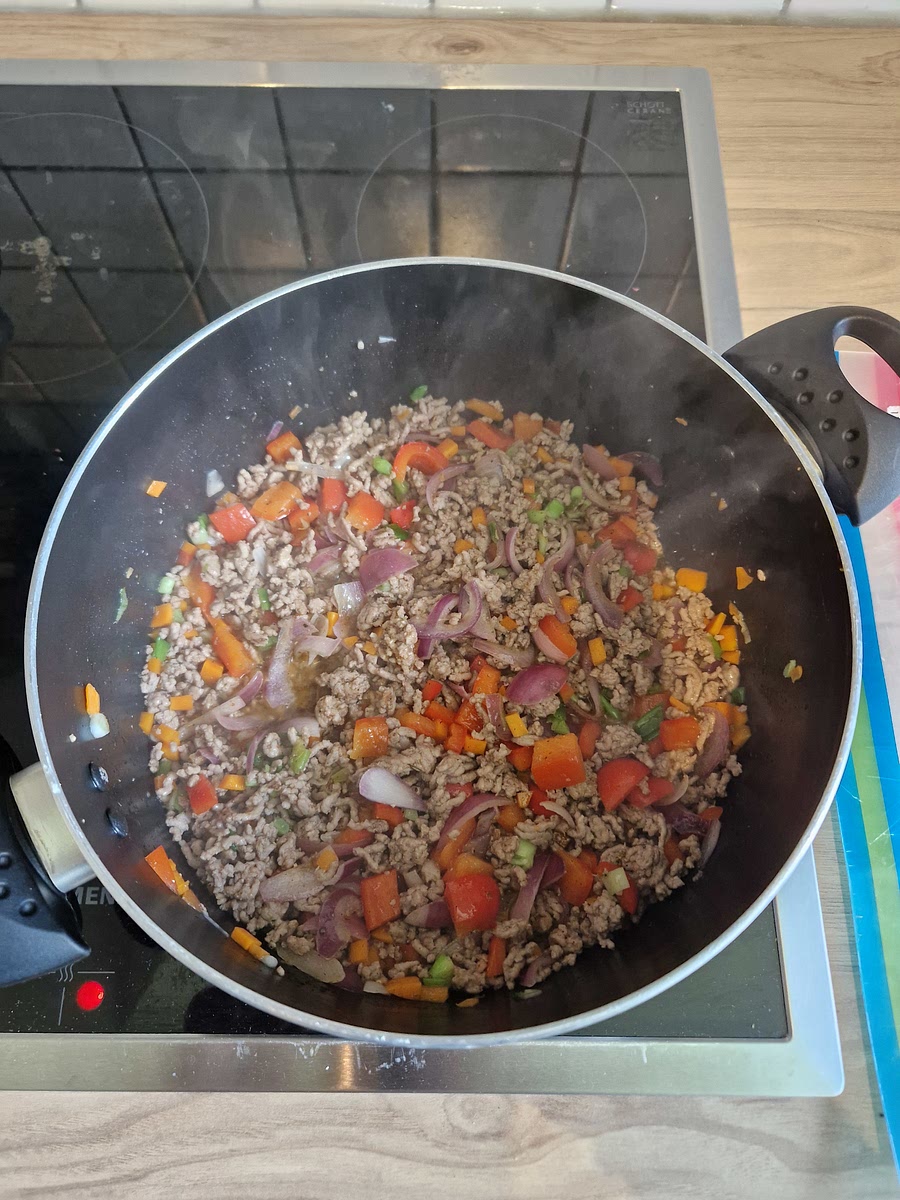 Hack, Paprika, Zwiebel, Möhre und Frühlingszwiebeln im Topf anbraten.