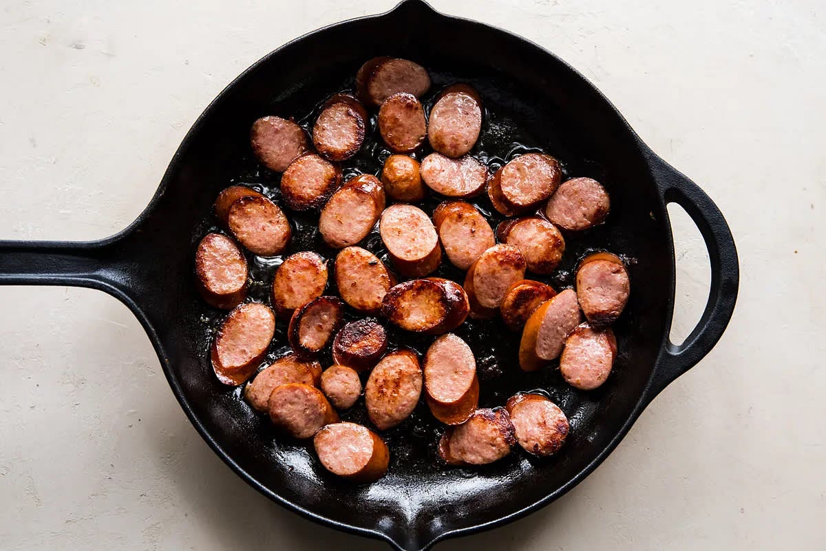 In a 12-inch skillet, heat olive oil over medium-high heat. Add the sausage and cook on both sides until browned, about 4-5 minutes. Set the sausage aside.