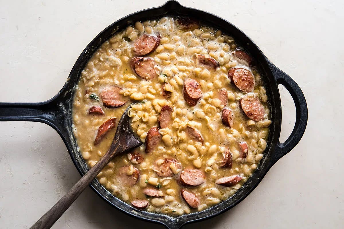 In a medium bowl, smash remaining beans with a fork until a thick paste is formed. Add the smashed beans back into the skillet and stir to combine. Simmer until the beans are heated through and the stock is simmering, about 2-3 minutes.