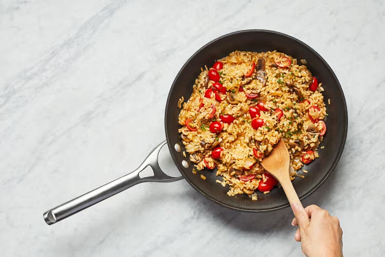 • Once risotto is done, stir in mushrooms, tomatoes, garlic herb butter, half the Parmesan, and half the chives (save remaining Parmesan and chives for serving). Cook until tomatoes are softened, 2-3 minutes. TIP: If risotto is too thick, stir in another splash of water or stock. • Turn off heat. Stir in a pinch of chili flakes if desired.