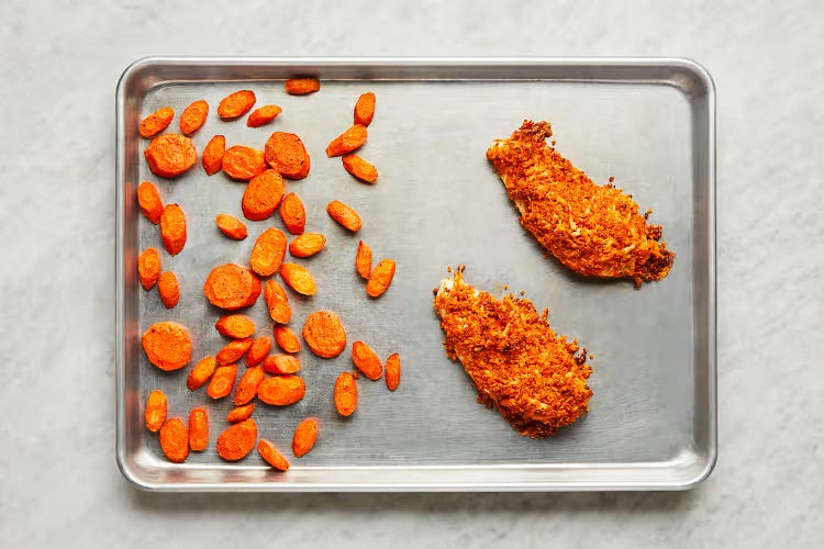 • Meanwhile, pat chicken* dry with paper towels and season with salt and pepper. Mound tops of chicken with panko mixture, pressing firmly to adhere. • Once carrots have roasted 5 minutes, remove sheet from oven. Carefully place chicken, coated sides up, on empty side. (For 4 servings, leave carrots roasting; roast chicken on a second oiled sheet on middle rack.) • Roast on top rack until chicken is golden brown and cooked through and carrots are tender, 15-18 minutes.