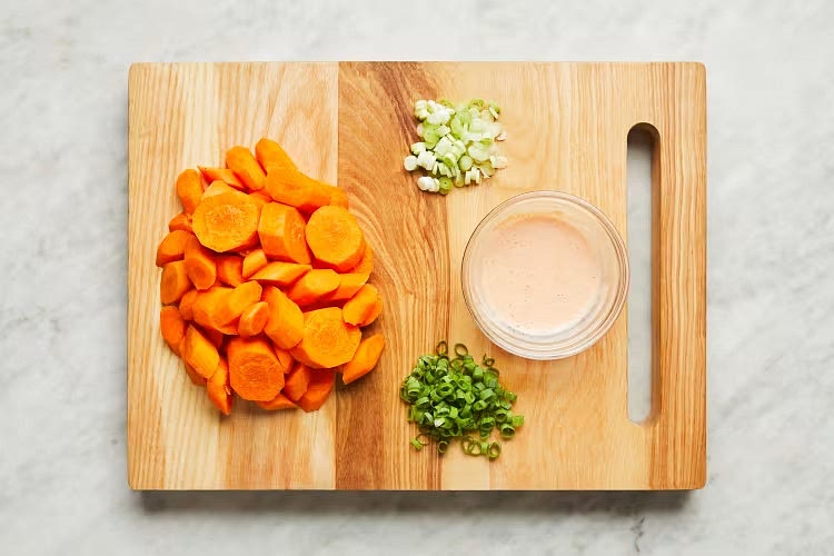 • Adjust rack to top position (top and middle positions for 4 servings) and preheat oven to 425 degrees. Wash and dry produce. • Trim, peel, and cut carrots on a diagonal into 1⁄2-inch-thick pieces. Trim and thinly slice scallions, separating whites from greens. • In a small bowl, combine half the sour cream, 1⁄2 tsp Frank’s Seasoning Blend (1 tsp for 4), and a big pinch of salt. (Be sure to measure the Frank’s Seasoning— you’ll use the rest in Step 2.) Stir in water 1 tsp at a time until mixture reaches a drizzling consistency.