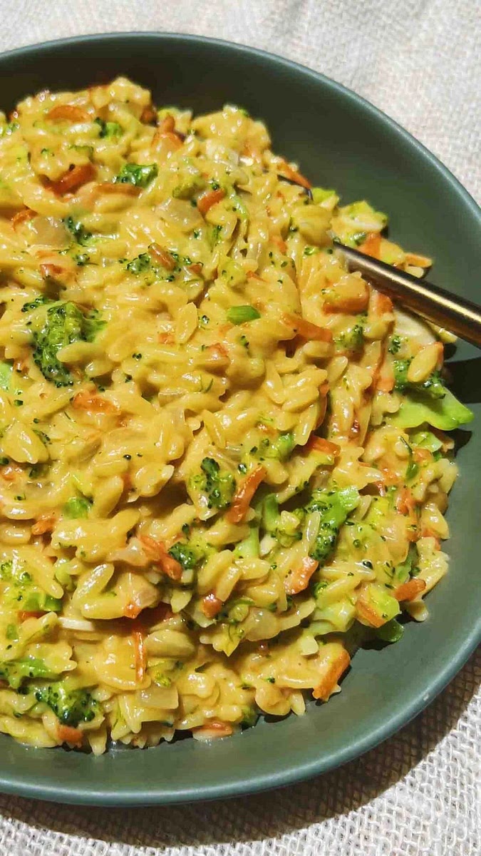 Add garlic and shredded carrots and cook down for another few minutes or until the garlic is starting to get tender and fragrant.
Add uncooked orzo and the stock and stir. Once simmering, put the lid on and let cook for about 6 minutes.
Remove lid and add broccoli and milk and stir once more. Put the lid back on and let the dish cook for 4 more minutes or until the pasta is al dente and the broccoli is tender.
Add the cheese and stir. Season with salt and pepper to taste. Enjoy!