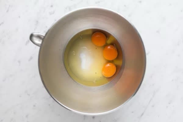 Per preparare il plumcake allo yogurt, iniziate a montare con le fruste elettriche le uova con lo zucchero in una ciotola fino a ottenere un composto chiaro e spumoso. Aggiungete l’olio a filo continuando a montare, seguito dalla scorza di limone grattugiata.