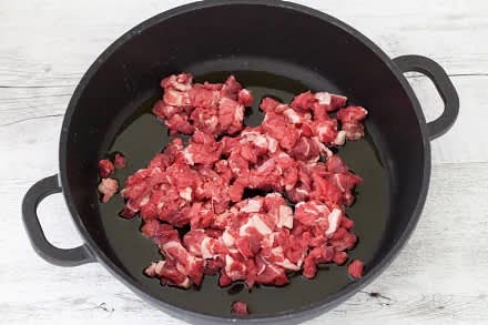 Per realizzare i burrito con carne iniziate a tagliare la carne a pezzetti con un coltello affilato e fatela rosolare in una capiente casseruola con l'olio. Salate e pepate. Quando sarà diventata uniforme, ritiratela e tenetela al caldo in un piatto. Nello stesso fondo di cottura fate appassire l'aglio e la cipolla affettata sottilmente fino a quando sarà diventata trasparente.