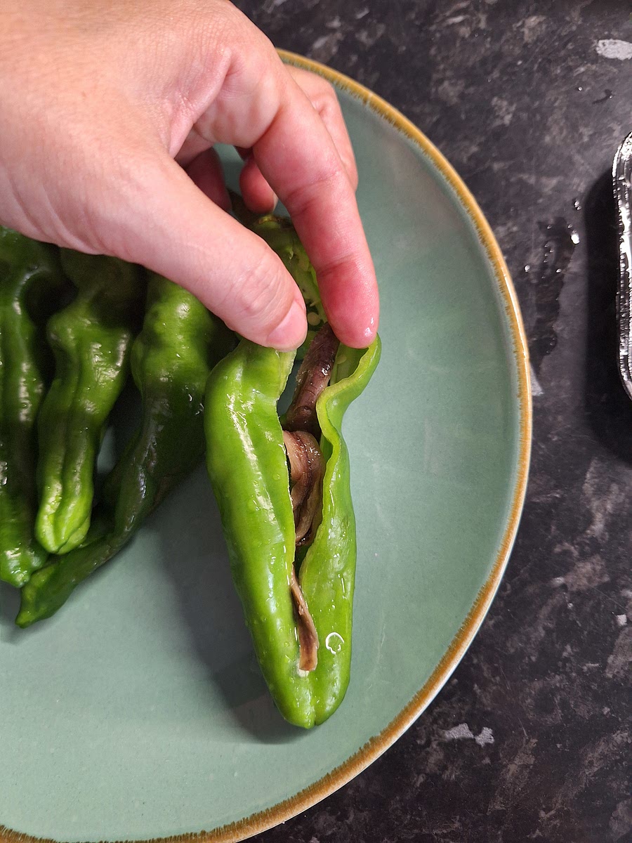 Hacer un corte a lo largo, abriendo completamente el pimiento, e introducir 2 ó 3 anchoas (dependiendo del tamaño)