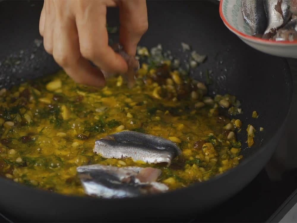 Aggiungi i pezzettini di sarde e condisci con prezzemolo tritato, sale e pepe nero. Lasciamo cuocere a fiamma media fino a far sfaldare il pesce, girando di tanto in tanto.