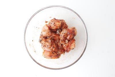 While the lentils are cooking, dice your chicken breast strips into small bite-sized pieces.
Add the diced chicken to a bowl with your ground paprika, black sesame seeds and a pinch of salt and give everything a good mix up – this is your marinated chicken.
Chop your coriander finely, including the stalks.
Chop your baby plum tomatoes in half