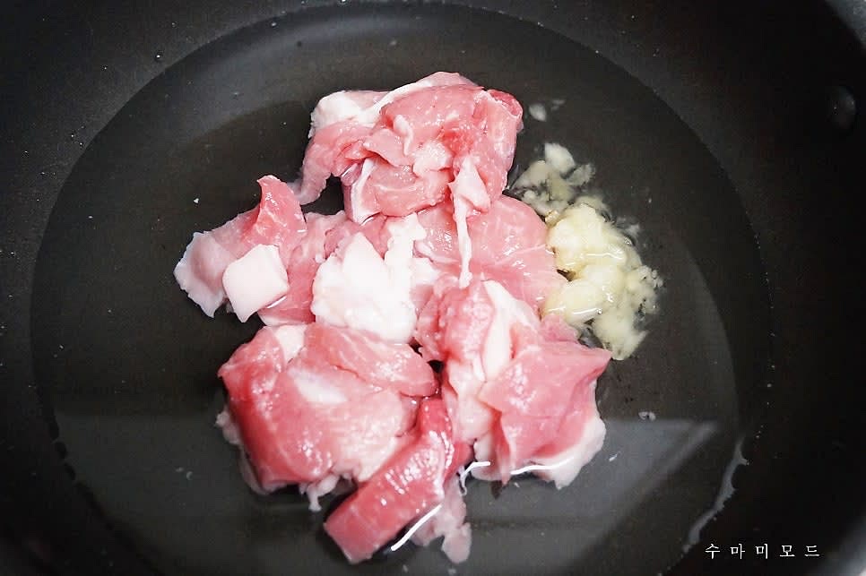 웍에 찌개용 돼지고기 300g 을 넣고 다진마늘 한스푼과 물 2컵(400ml) 을 부어주세요.