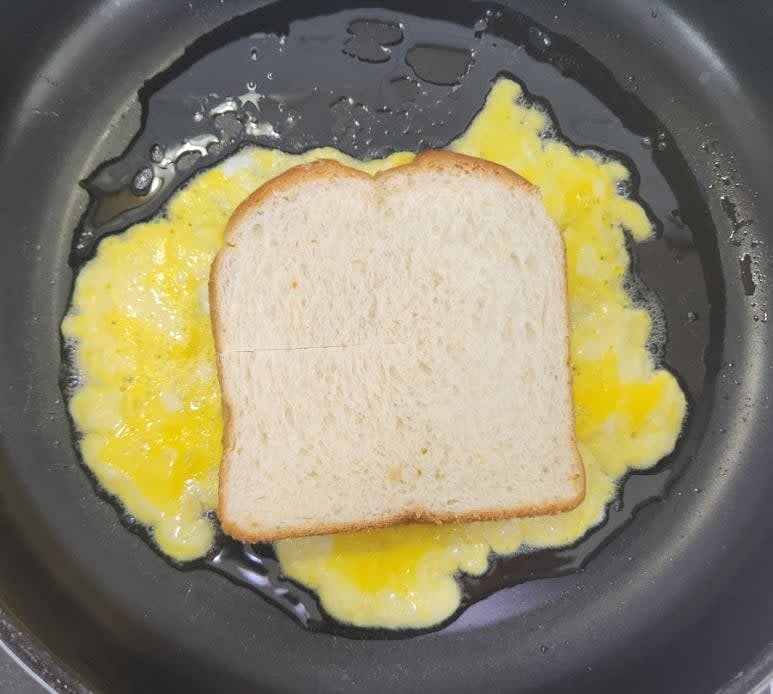 중약불로 달군 팬에 식용유를 넉넉히 두르고 계란 물의 반을 부어 식빵보다 더 크고 넓게 펼친 뒤 계란물이 반쯤 익으면 식빵의 칼집 낸 부분이 위로 향하도록 올려 주세요.