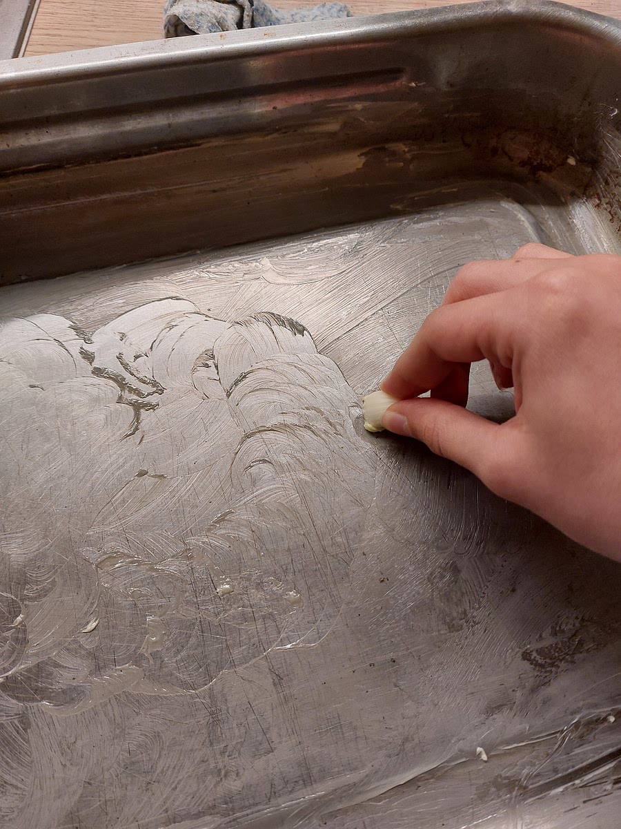 Knoblauch abziehen, halbieren und die gefettete, flache Auflaufform mit dem Knoblauch einreiben