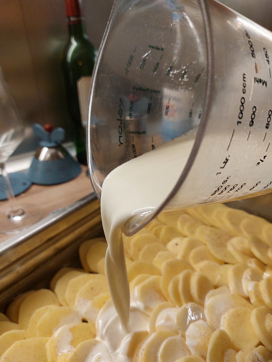 Milch mit Sahne verrühren und über die Kartoffelscheiben gießen