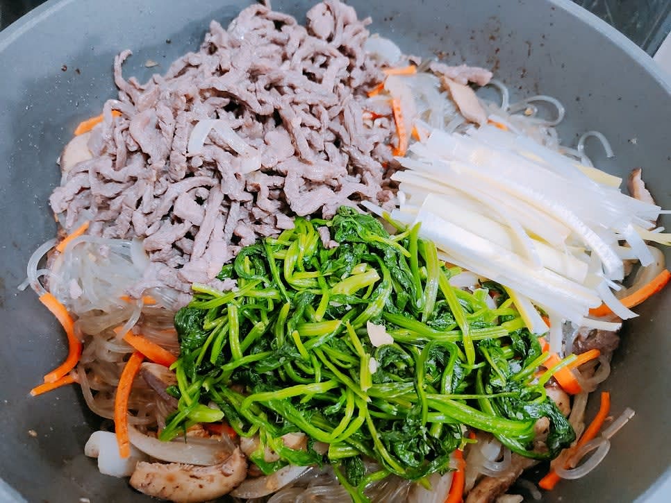 양파가 익으면 한쪽으로 몰아준 후 들기름 1큰술을 넣은 뒤 약불에 삶은 당면을 넣고 볶다가 만들어둔 양념장을 넣고 잘 섞어준 후 시금치와 대파를 넣고 볶아서 완성해 주세요 (노추 1큰술 넣어 잘 섞어 주세요)