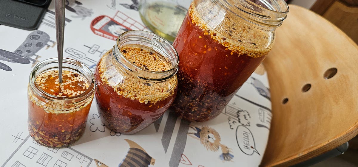 Ensure that the oil is piping by reheating it to 160c. And with all of your precious chili oil solids nicely mixed together and separated into jars, pour the hot oil on top of the ingredients in the jars. You should see and hear a sizzle but not smoke! Don't burn your precious ingredients in this last step! If oil is too hot, wait for it to cool a little before pouring.