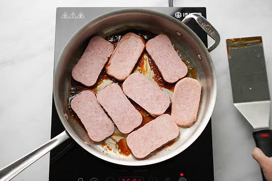 Add the spam slices and cook for about 1 minute and then turn them over to make sure all sides of the spam are coated. Cook and occasionally turn the spam to prevent from burning for about 10 minutes or until the Spam begins to caramelize or turn golden brown.
